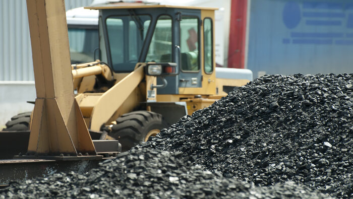 Pile of coal with an excavator behind it